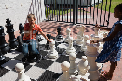 Boy and girl playing together large chess