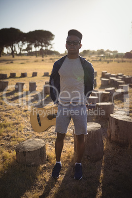 Full length of man holding guitar while standing at forest