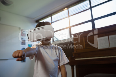 Close up of boy wearing virtual reality simulator gesturing while standing against piano