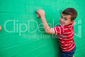 Portrait of smiling boy climbing wall at playground