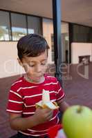 Close up of boy eating banana while sitting by table