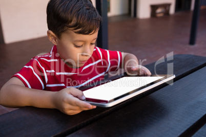 Close up of boy using digital tablet while sitting at table