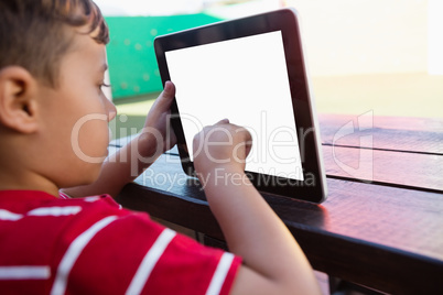 Close up of boy touching digital tablet while sitting at table