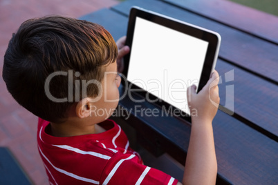 High angle view of boy using digital tablet while sitting at table