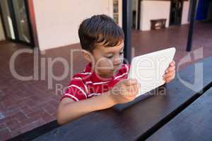 Close up of cute boy using digital laptop while sitting at table