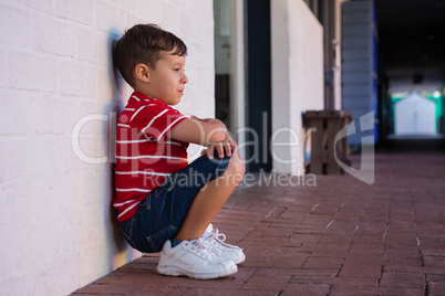 Side view of boy crouching by wall