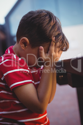 Close up of boy with hands covering face sitting at table