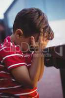 Close up of boy with hands covering face sitting at table