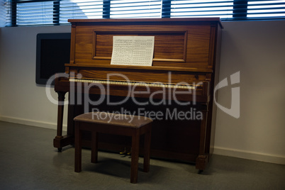 Wooden piano against window in clasroom