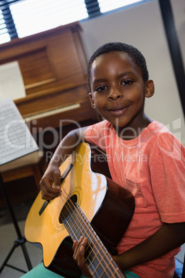 Portrait of boy holding guitar in class