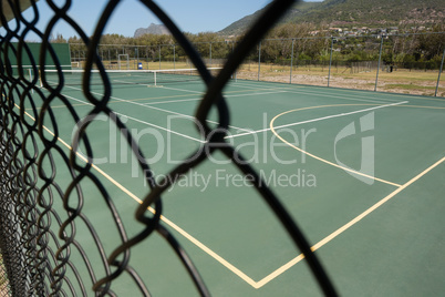 Empty tennis court seen through fence