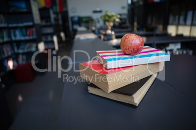 Apple on stack of books in liabrary