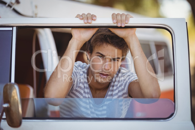 Portrait of serious young man leaning on van