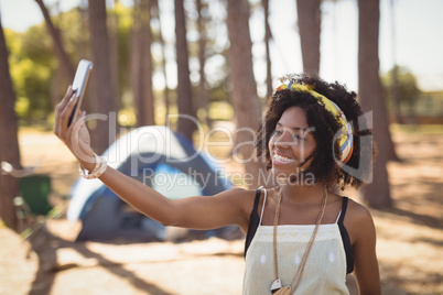 Smiling woman clicking selfie while standing against tent