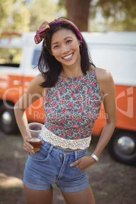Portrait of young woman holding beer glass on field