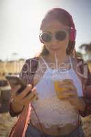 Young woman listening to music while having drink