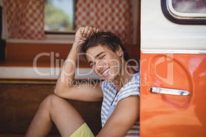 Smiling young man looking away while sitting in van