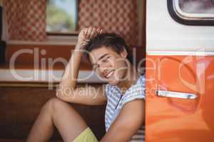 Smiling young man looking away while sitting in van