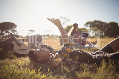 Young man using mobile phone while lying on grassy field