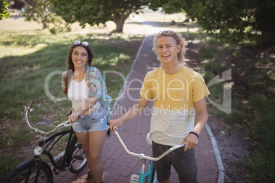 Portrait of smiling man and woman standing with bicycle