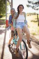Playful couple sitting on bicycle at footpath