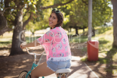 Portrait of smiling woman riding bicycle on footpath