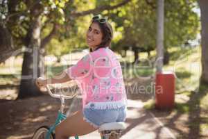 Portrait of smiling woman riding bicycle on footpath