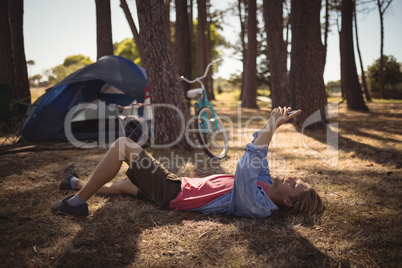 Side view of man using smart phone while lying on field