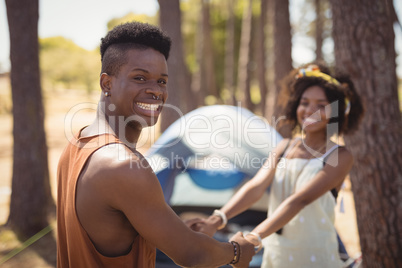 Portrait of happy couple holding hands while standing against tent