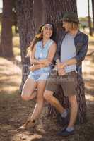 Cheerful couple standing by tree trunk
