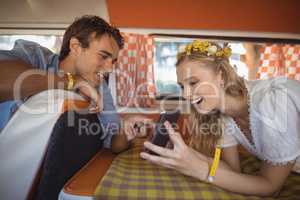 Happy woman showing mobile phone to man in van