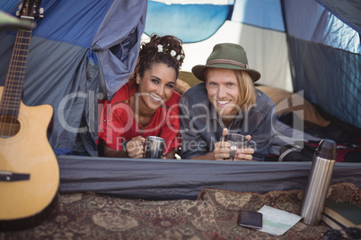 Smiling couple having tea in tent