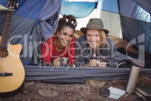 Smiling couple having tea in tent