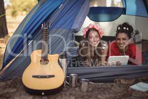 Smiling female friends relaxing in tent
