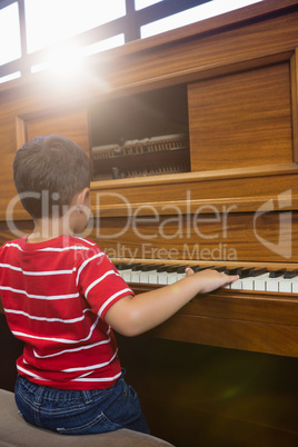 Rear view of boy playing piano in classroom