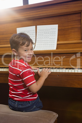 Portrait of smiling boy playing piano while sitting in classroom