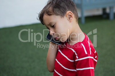 Close up of boy talking on mobile phone while standing on field