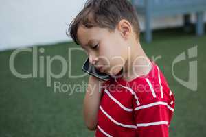 Close up of boy talking on mobile phone while standing on field