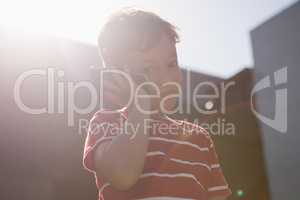 Low angle view of boy talking on mobile phone while standing against sky