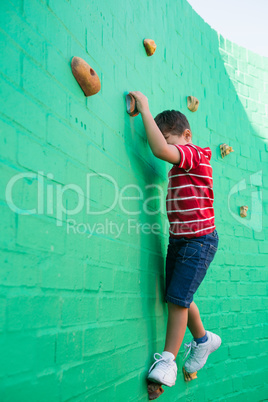 Cute boy climbing wall at playground