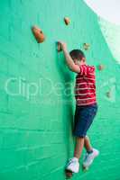 Cute boy climbing wall at playground