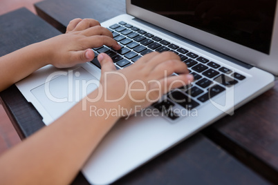 Cropped image of boy using digital laptop while sitting at table