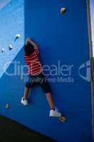 Rear view of boy climbing blue wall at playground