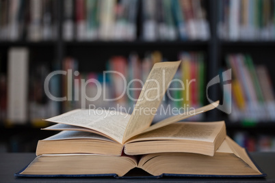 Stack of books on table against shelf