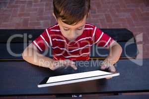 Boy touching digital tablet while sitting at table in school