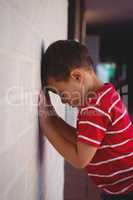 Side view of sad boy leaning on wall