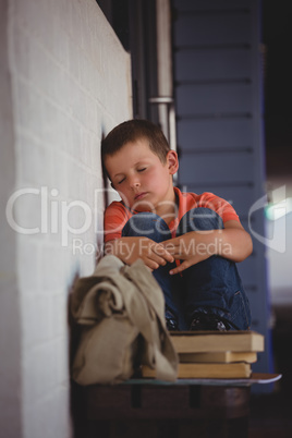 Boy sleeping while sitting on bench by wall