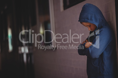 Boy standing alone by wall in corridor