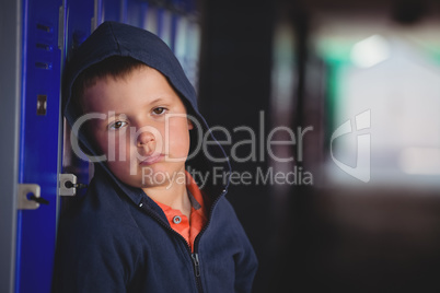 Portrait of sad boy leaning on locker