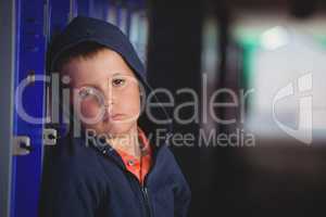 Portrait of sad boy leaning on locker